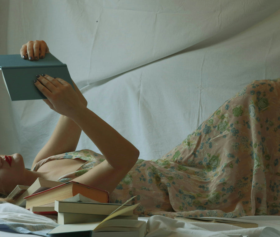 A woman reading a book in bed as part of a calm bedtime routine