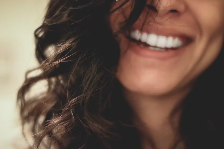 A close up of a smiling woman with long wavy hair.
