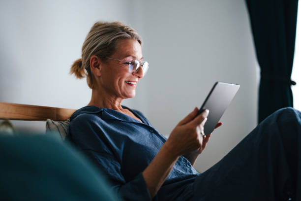 A smiling woman in her 50s relaxing in a chair at home in the evening