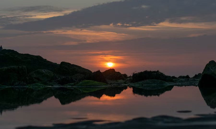 A calm sunset reflected in still water at dusk.