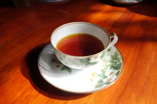 A cup of herbal tea on a wooden table in warm evening light.